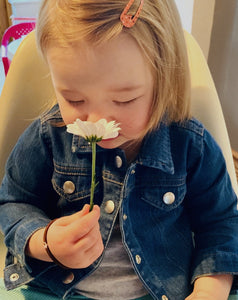 baby girl smelling flower 