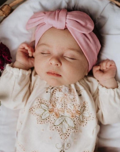 Baby asleep wearing a pink headband 