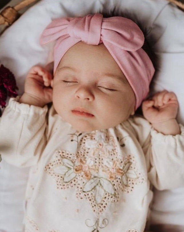 Baby asleep wearing a pink headband 