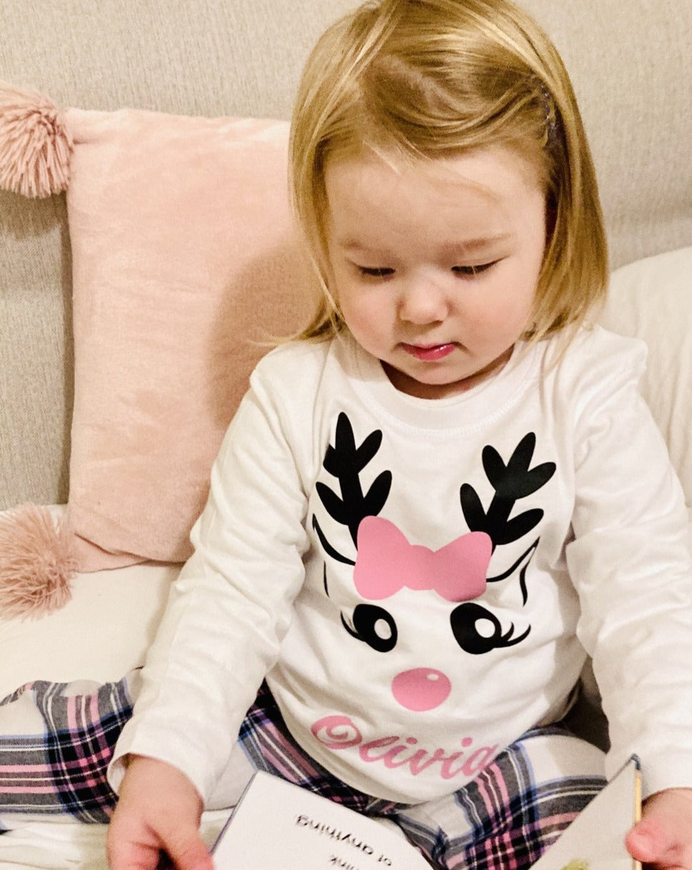 toddler in pink check and reindeer wit bow PJS