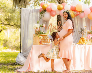 Pregnant woman at baby shower and little girl kissing tummy 